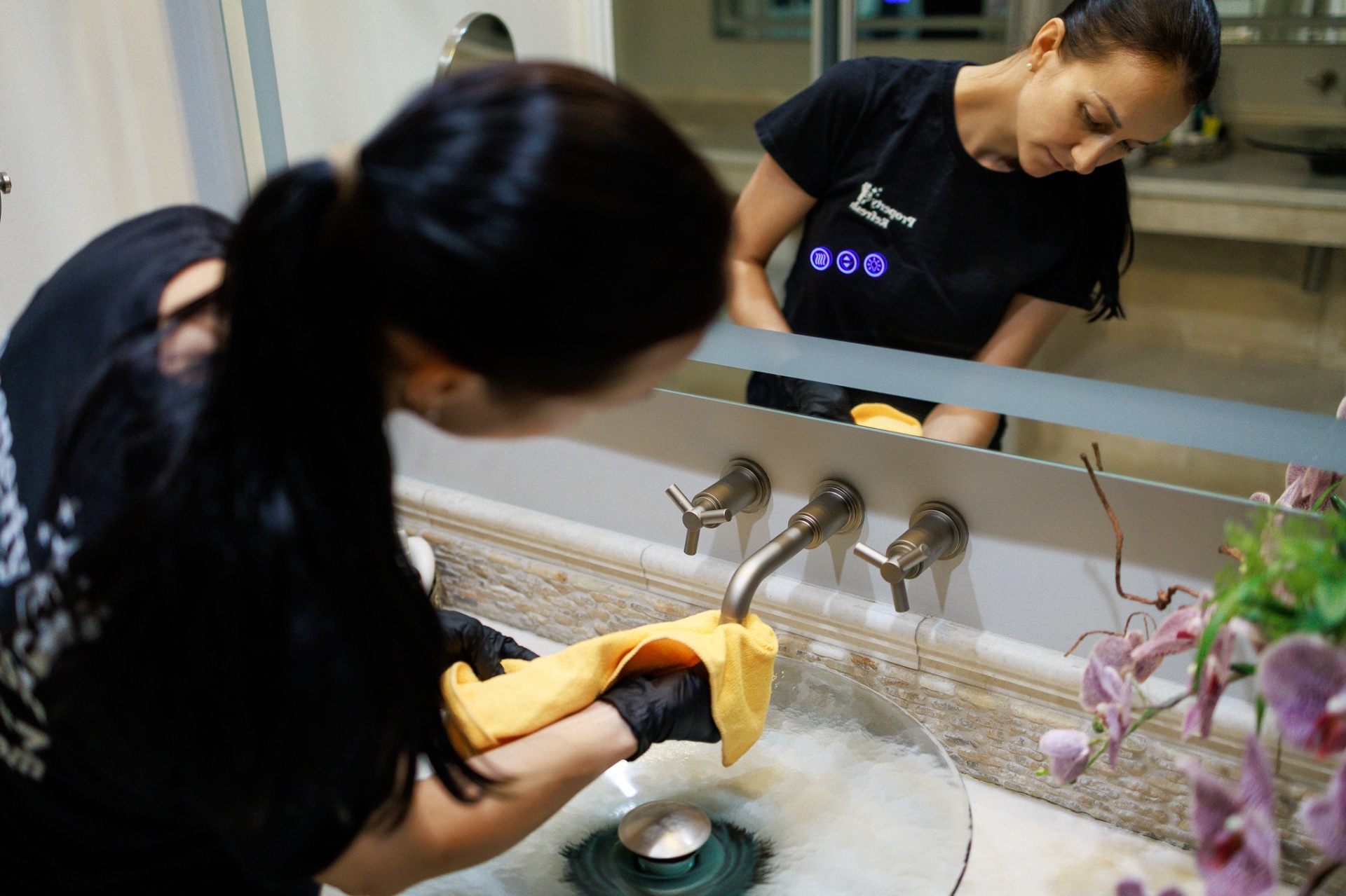 Cleaner polishing a bathroom faucet and sink before holiday guests arrive